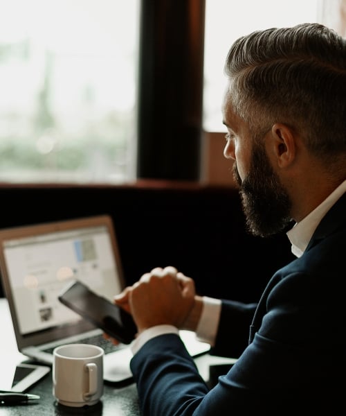 man in a suit working on his laptop and phone